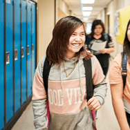 A girl walking through the hallways of her school talking to a friend