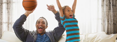 A man and his son celebrate while watching a televised basketball game