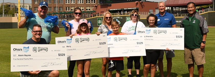 2021 Dayton Dragons MVP winners 3 Families standing on baseball field with oversized checks