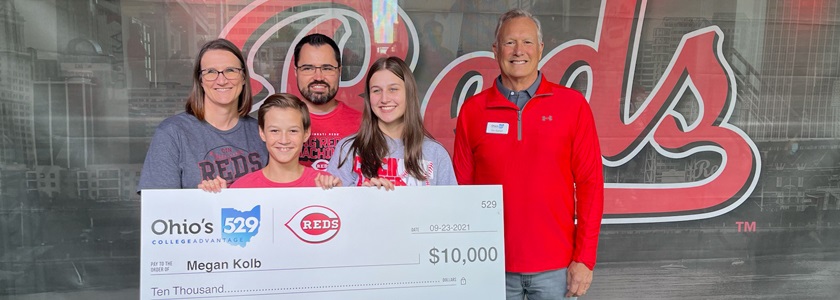 2021 Reds College Savings Grand slam winner Family holding oversized check in front of Cincinnati Reds signage