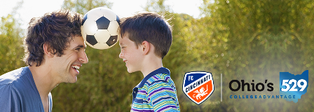 Father and young son balance soccer ball between their heads