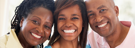 Mother, teenaged daughter, and father smile broadly  at the camera