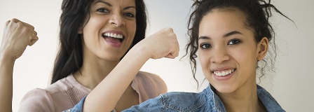 Mother and teenage daughter flex and smile at the camera