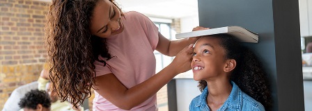 Mom measuring how tall her daughter has grown against a wall