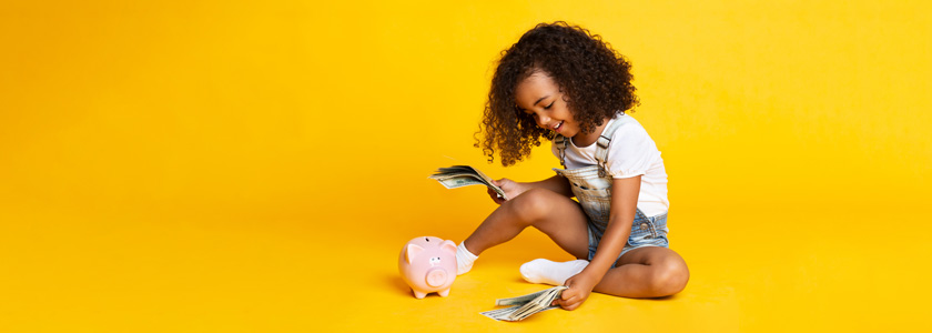 Little girl getting ready to place money into her piggy bank