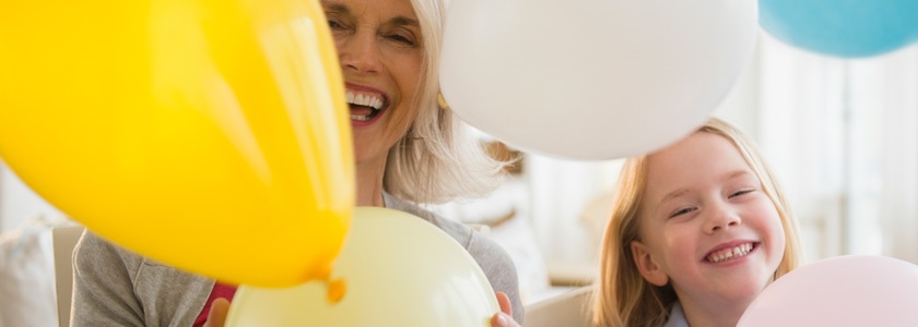 Laughing grandmother and granddaughter surrounded by balloons