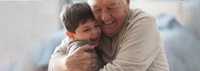 Laughing grandfather and grandson hugging