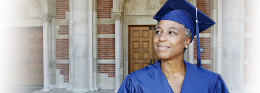 An older woman standing proudly in her mortar board and gown