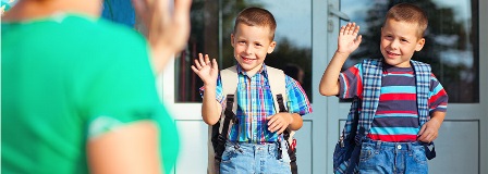 Twin boys waving goodbye to their Mom in front of school entrance