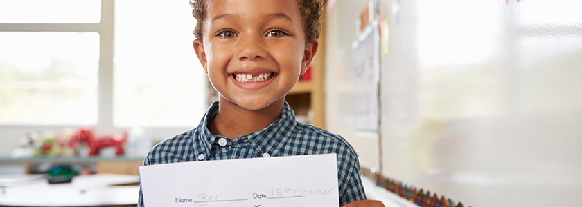 Smiling boy proudly holding up his paper