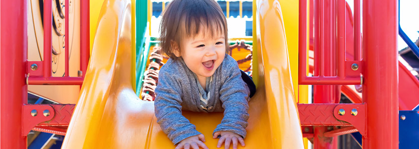 Laughing toddler coming down slide on her stomach