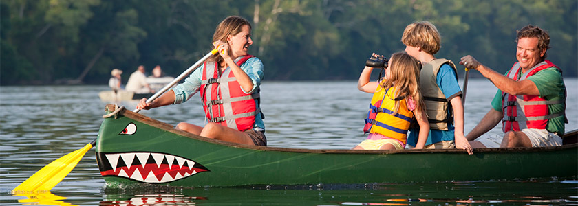 Family paddling in a canoe with a face at the bow