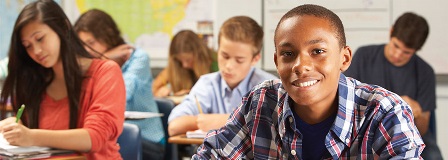 Student smiles at camera in busy classroom