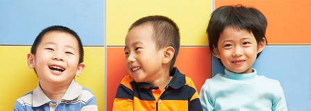 Three boys laugh in front of color square block wall
