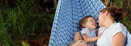 Mother and son smile at each other as the cuddle in a hammock