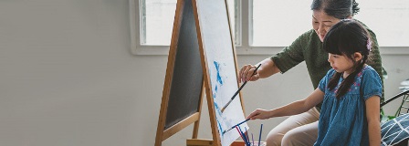 Grandmother and granddaughter painting together at easel