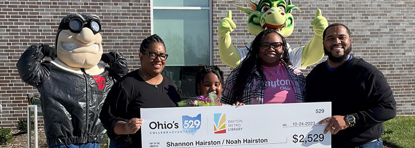 Dayton Metro Library Summer Challenge winner Noah Hairston and her family celebrates with Rudy and Heater at check presentation.