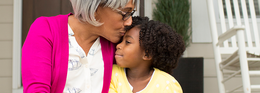 Grandmother kissing granddaughter's forehead