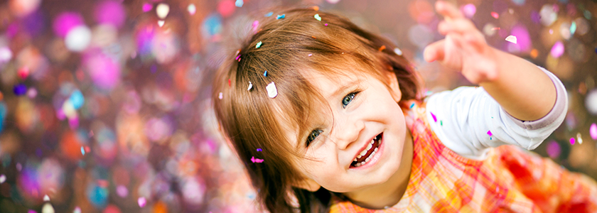 Little girl smiles at the camera as confetti falls around her