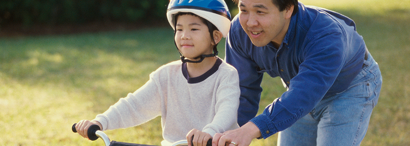It’s Never Too Late To Save In Ohio's 529 Plan Dad holds onto the back of a bike as his sons learns to ride without training wheels