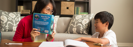 Mom looking over book at son while she quizzes him