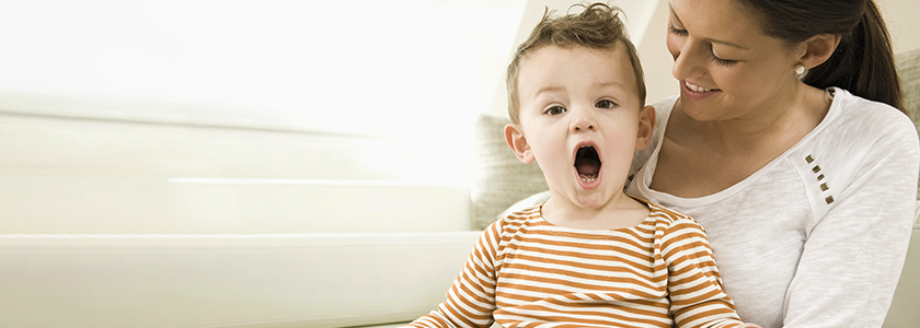 Mom smiling at laughing toddler on her lap