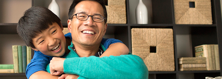 Smiling dad is hugged by his son
