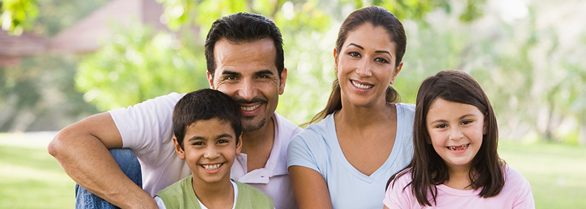 A family with a son and daughter sit under a tree