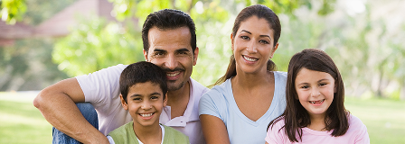 A family with a son and daughter sit under a tree