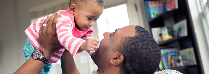 Dad smiles at his child who is staring at him.
