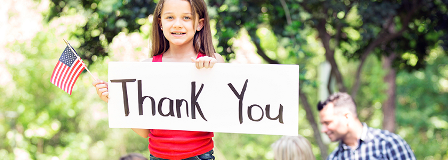 Young girls holding a sign with "thank you" written on it and an American flag