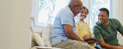 Grandfather, son, and grandson gather around tablet, talking with each other