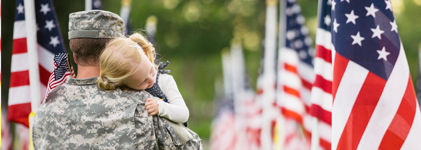 Young girl lays her head on her father's shoulder he carries her in field of flags
