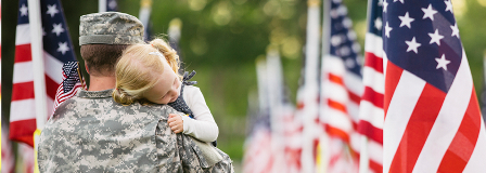 Young girl lays her head on her father's shoulder he carries her in field of flags