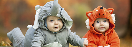 Two babies dressed up for Halloween. One is an grey elephant and the other a red fox.