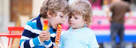 Two brother sharing their popsicles with each other at the fair
