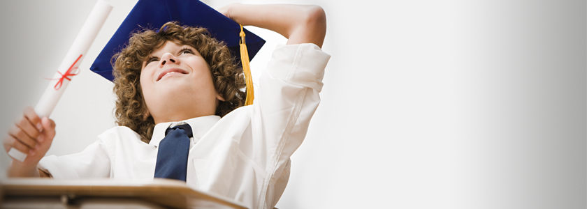 Younger boy wearing a graduation cap looking towards the sky