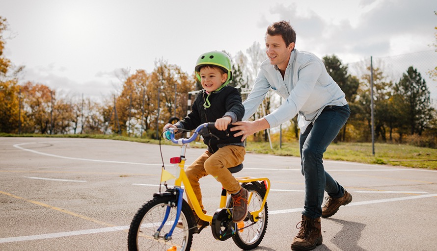 man pushing boy on bike