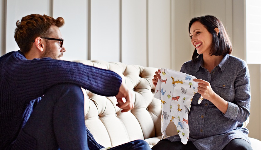 woman showing man baby outfit